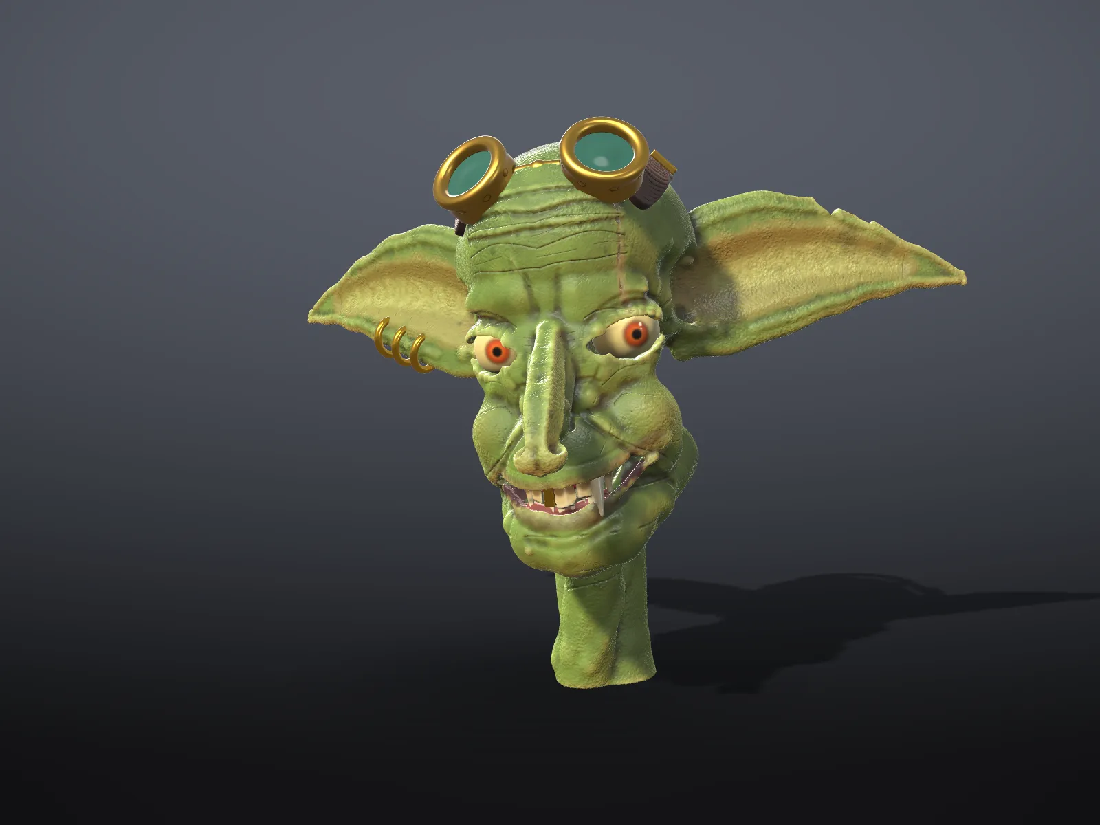 A grinning goblin head with large ears and goggles
